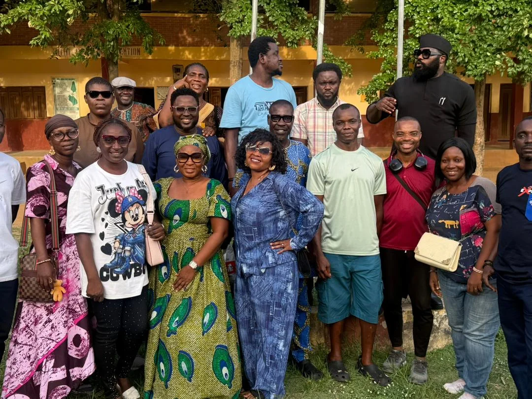 FGSCAA members posing as a group in front of the school, with a member in black at the back gesturing towards the camera.