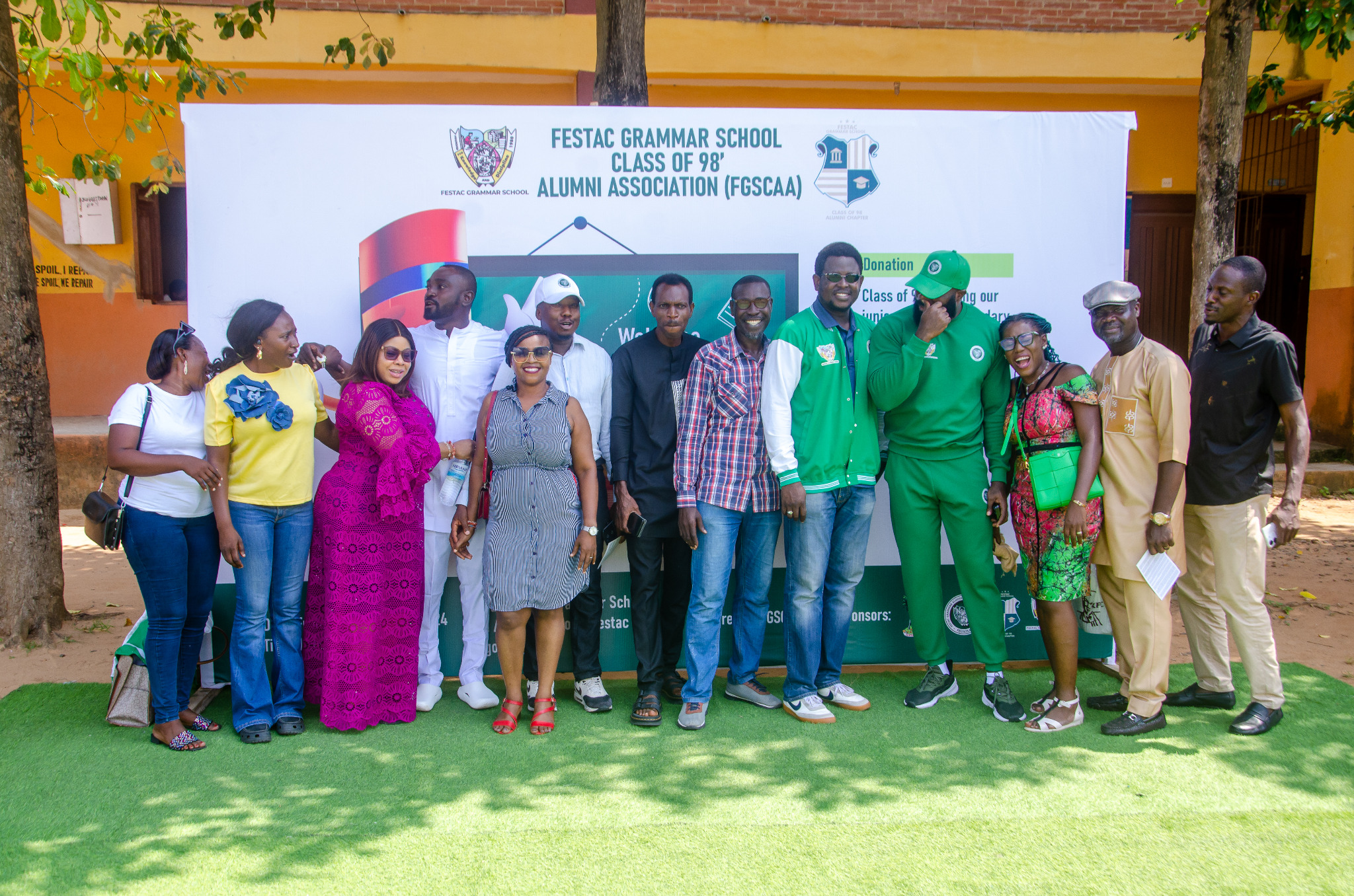 Alumni members photographed beside an association project backdrop