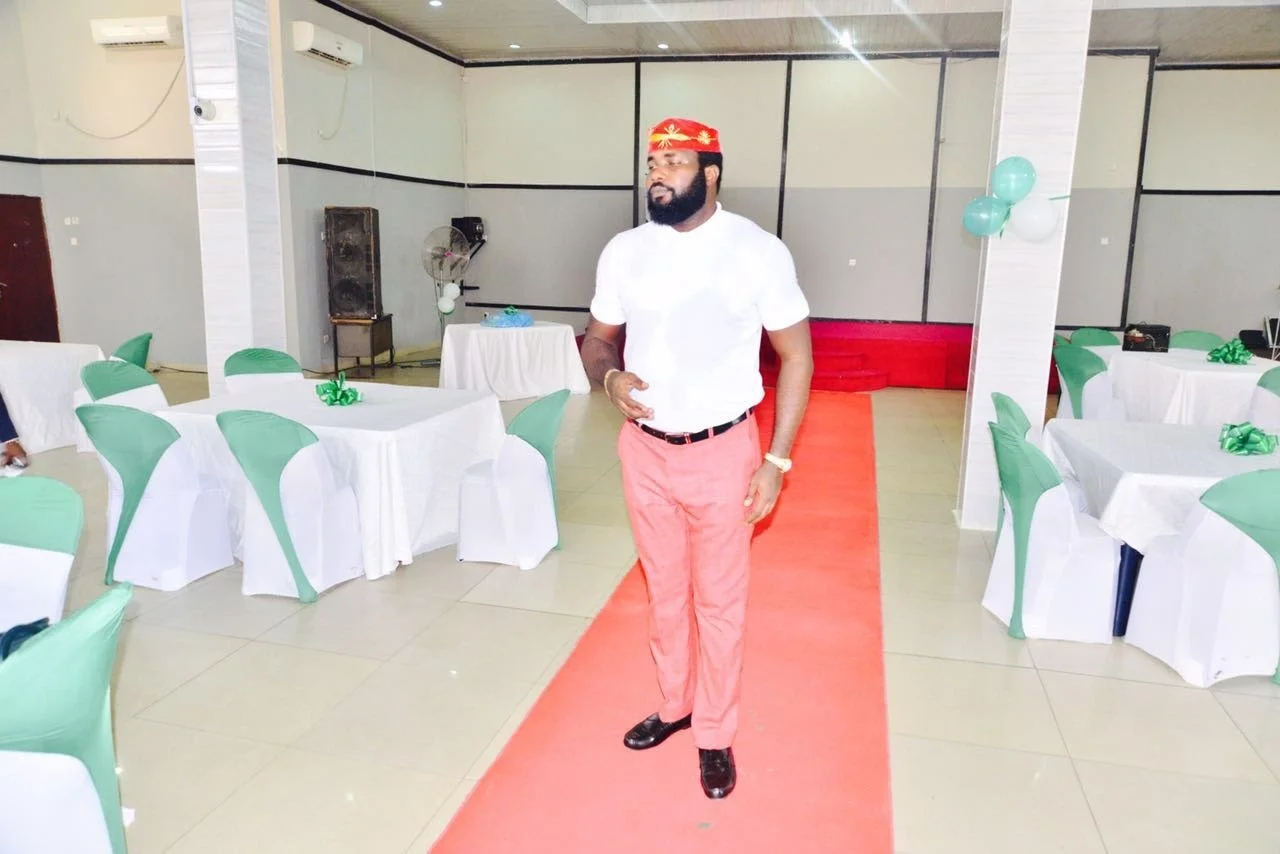 The hall at Frank Kids Park laid with a red carpet and tables dressed in white cloths with green chair covers and ribbons, with a member walking along the carpet.