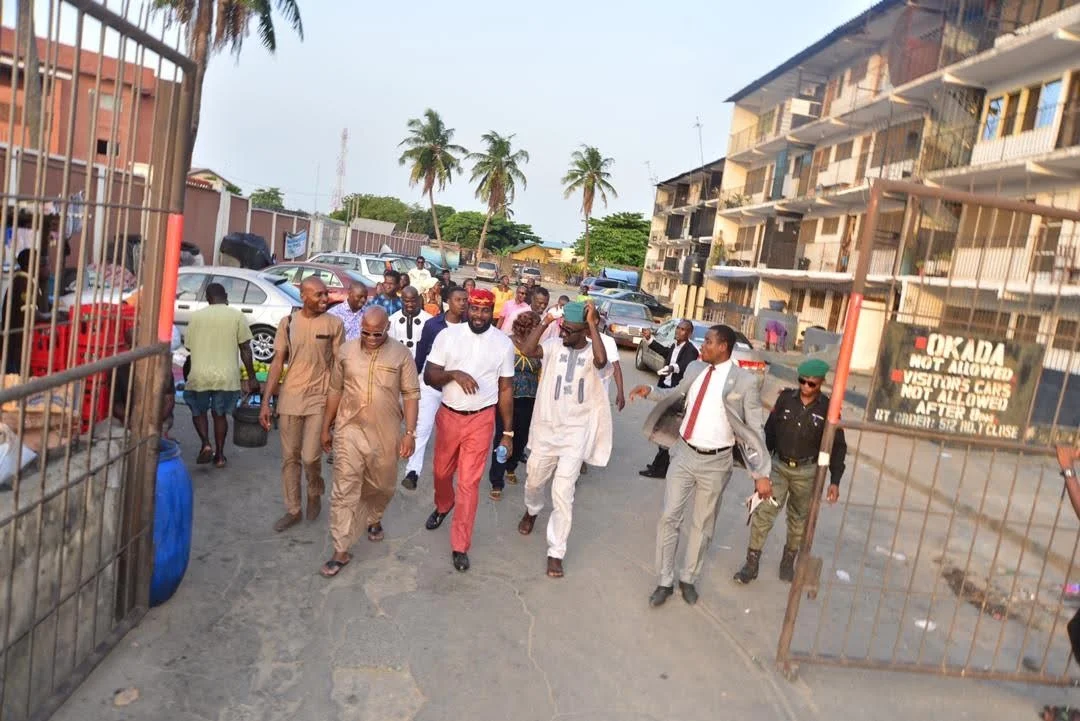 A group of members walking out through an open gate onto a Festac Town street, beside a sign reading “Okada not allowed”, after the inaugural meeting.