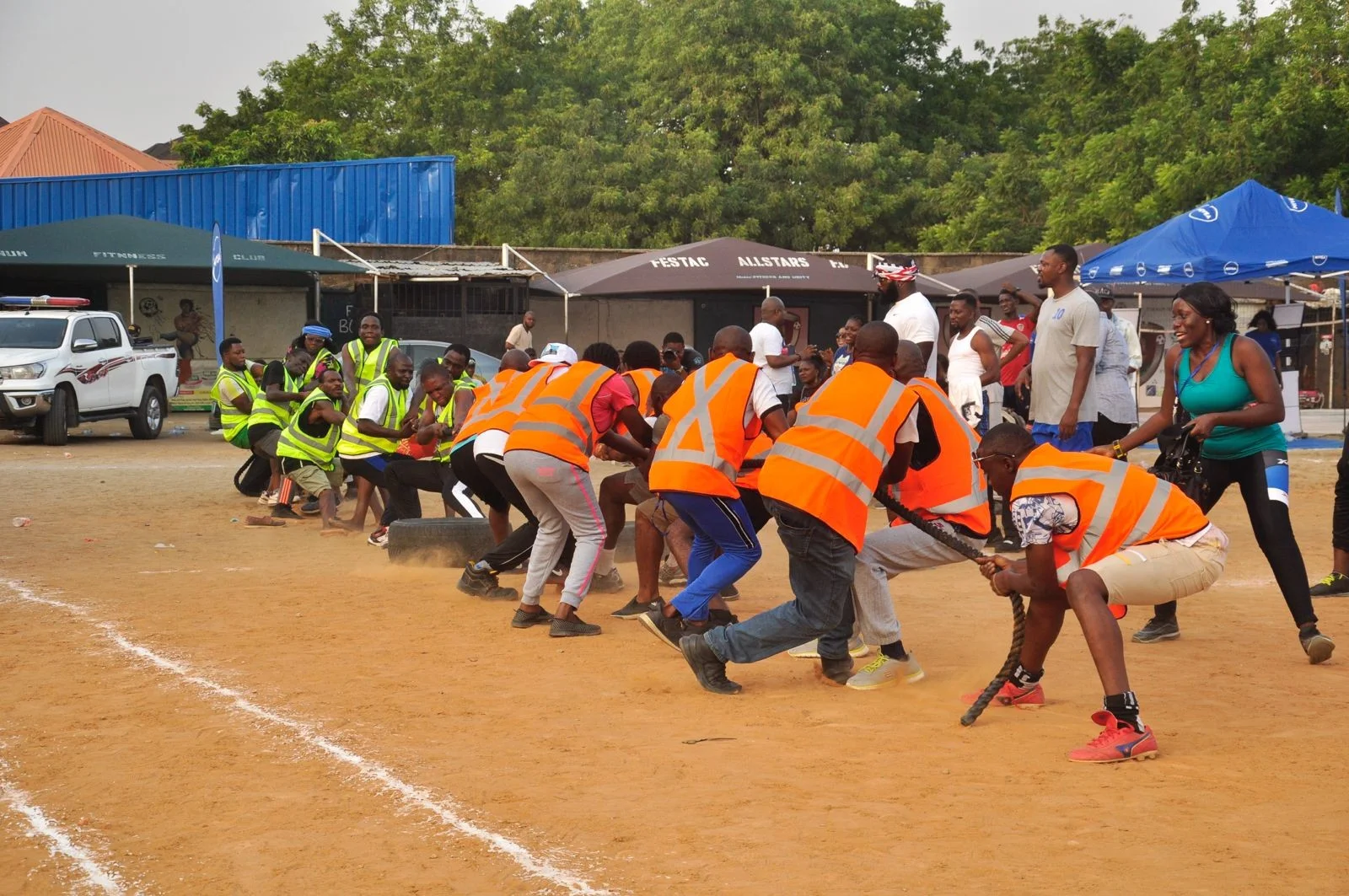 Two teams of FGSCAA members in yellow and orange vests competing in a tug-of-war on a sports ground during the 2020 Homecoming.