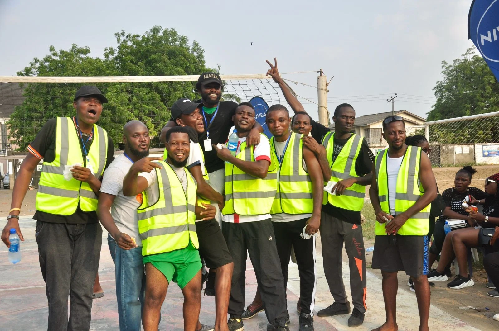 A participating group of FGSCAA members in yellow reflective vests celebrating beside a volleyball net.