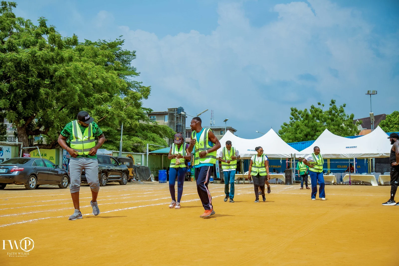 Wide view of FHA Field with participants walking on the running track and white tents in the background during the 2025 Homecoming.