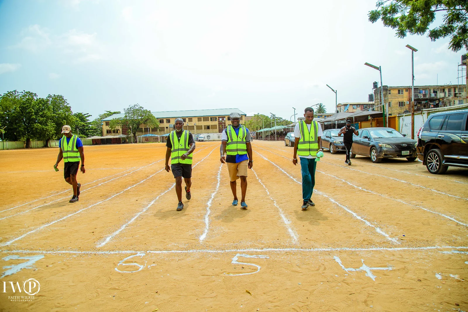 Four FGSCAA members walking down the numbered lanes of the running track during the 2025 Homecoming.