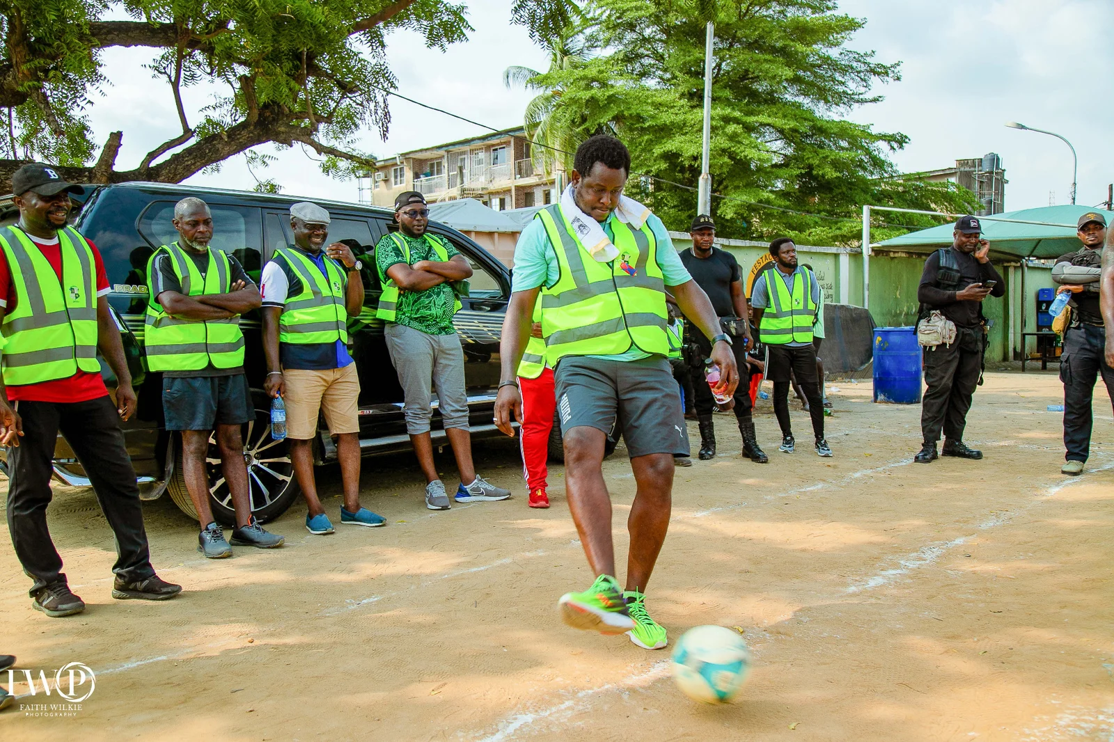 An FGSCAA member kicking a football while members in vests watch during the 2025 Homecoming games.