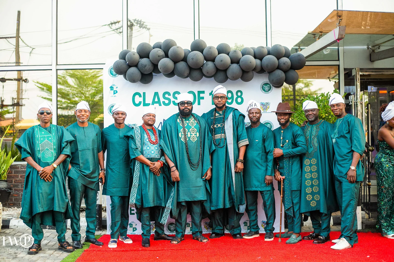 Ten FGSCAA members in green attire and white caps on the red carpet in front of the Class of 1998 backdrop and balloon arch.