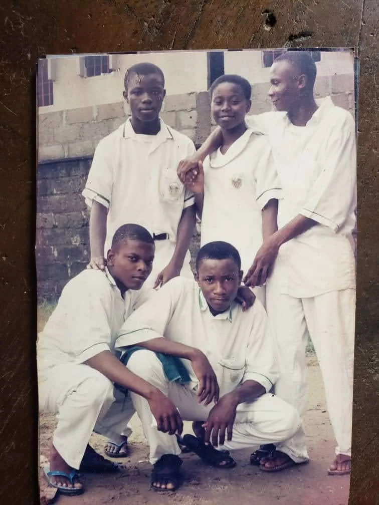 An original photographic print showing five students in white uniforms bearing the school badge, two crouching in front and three standing behind.