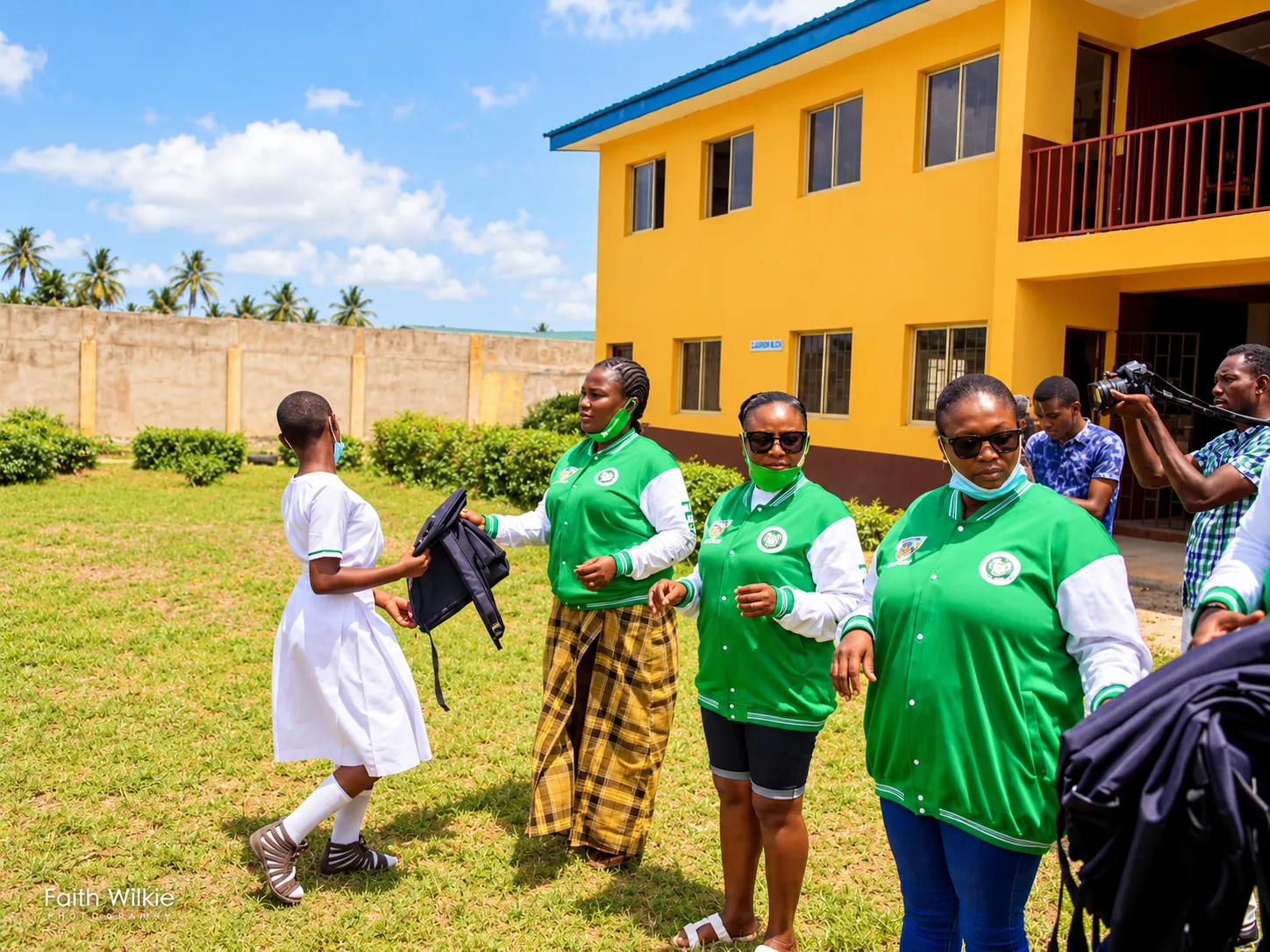 FGSCAA members handing a backpack to a student near the classroom block.