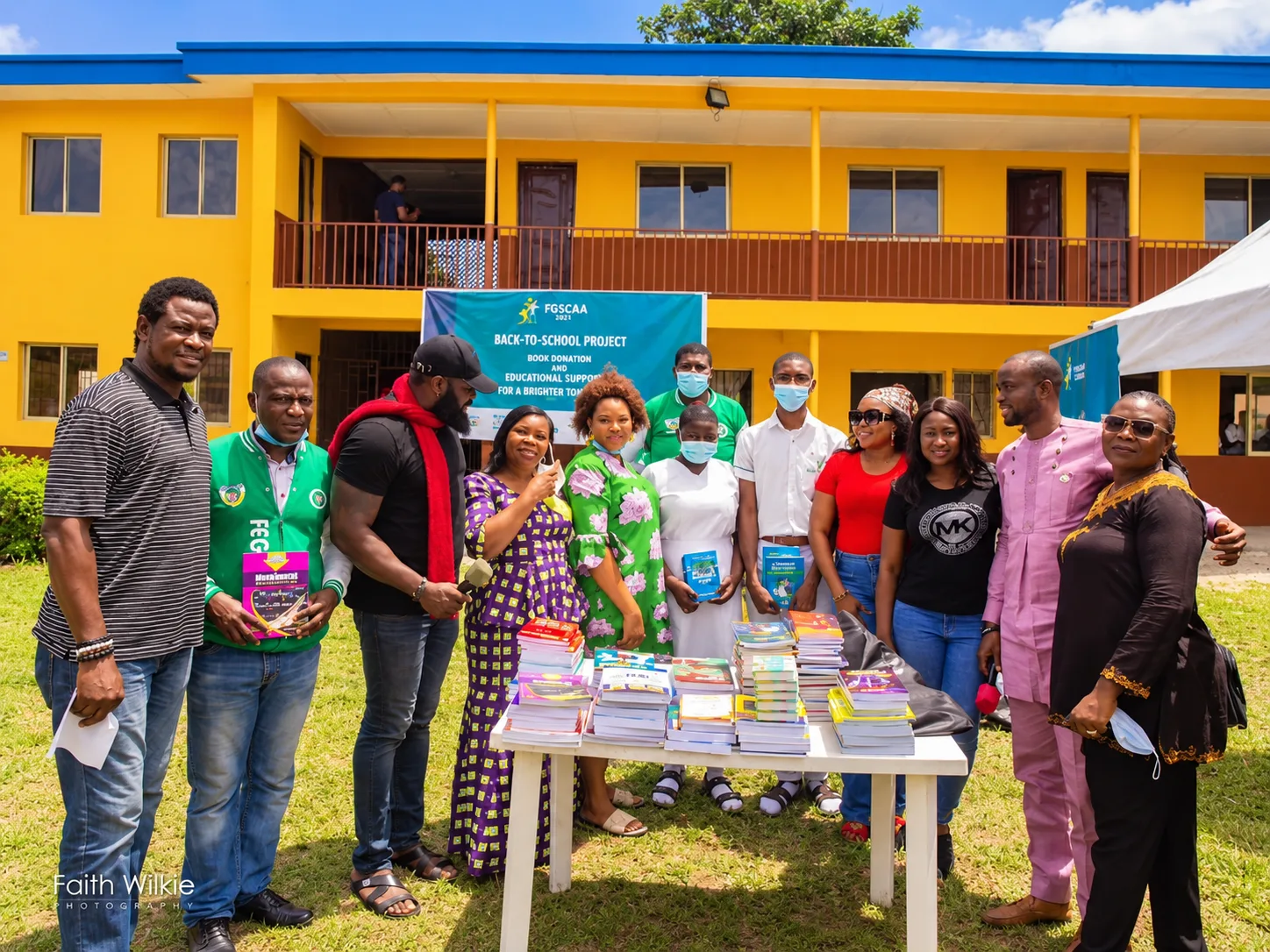 Organisers and students standing around a table of donated books under a Back-to-School Project 2021 banner.