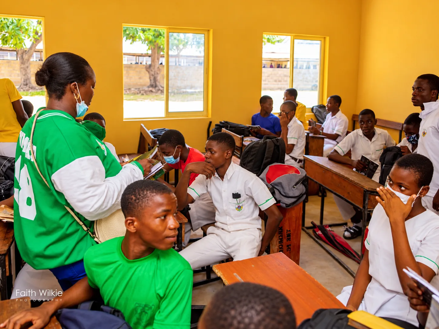 An FGSCAA member handing out books to students in a classroom during the 2021 Back-to-School Programme.
