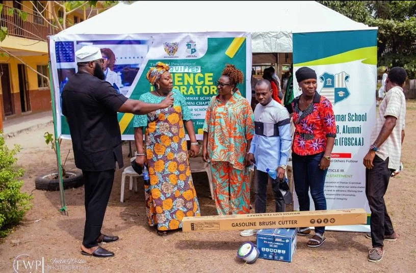 An FGSCAA representative gestures while addressing school representatives, with the boxed brush cutter resting on the equipment box in front of them.