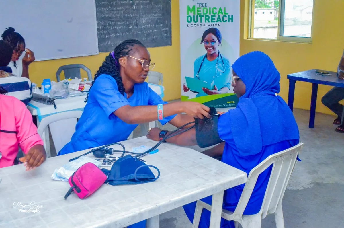A health worker fits a blood-pressure cuff on a participant in a blue hijab in front of the FGSCAA Free Medical Outreach and Consultation banner.