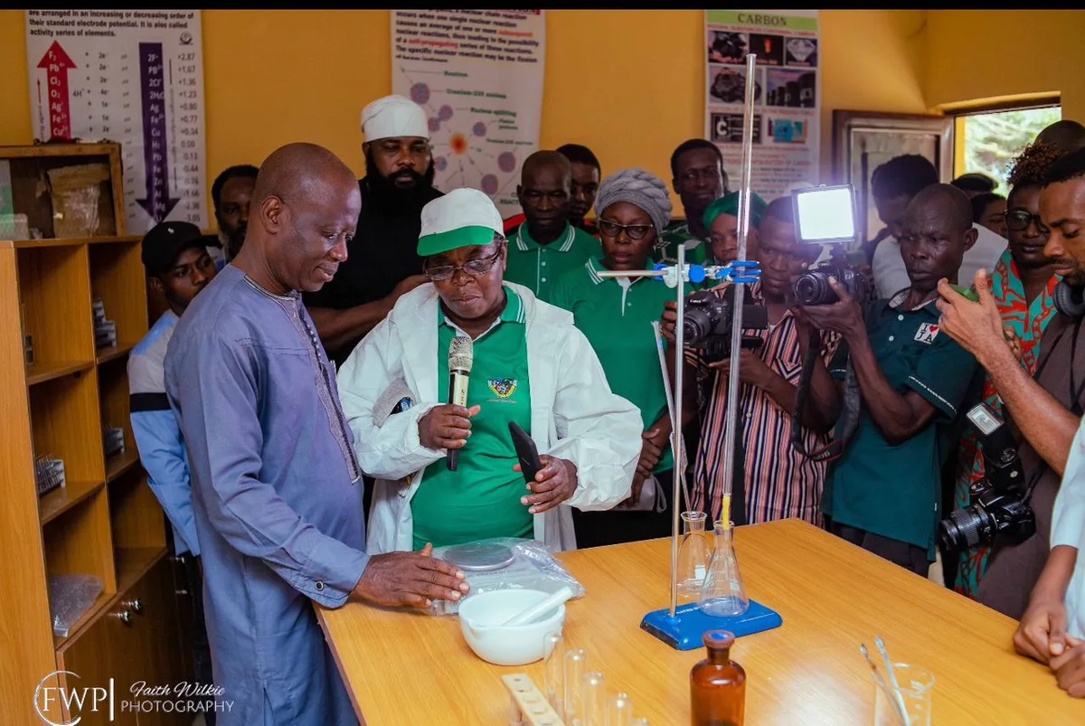 FGSCAA representatives and school staff inspecting laboratory apparatus at a workbench during the commissioning, watched by photographers and guests.