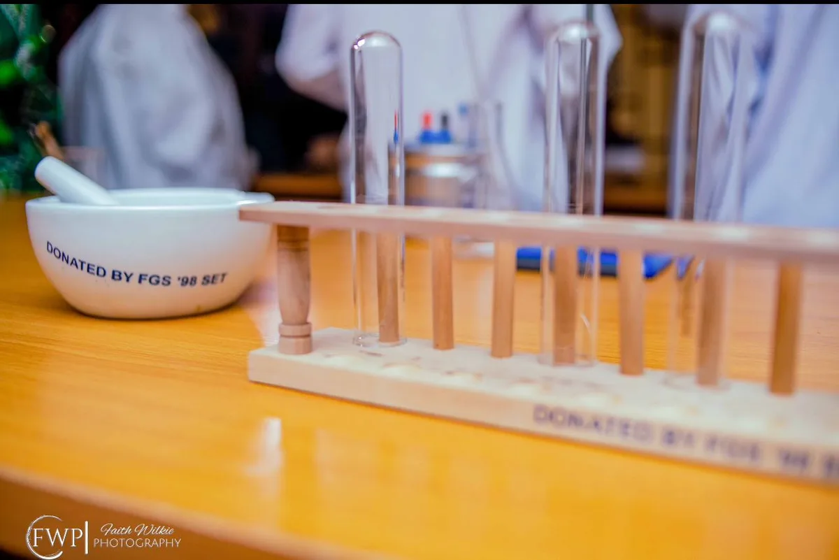 A mortar and pestle and a test-tube rack on a workbench, both marked “Donated by FGS ’98 Set”.