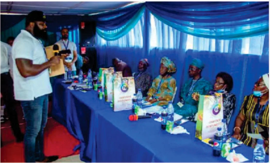 Officials and guests seated at a blue-draped table while a speaker addresses them during the 2021 FGSCAA Spelling Bee programme.